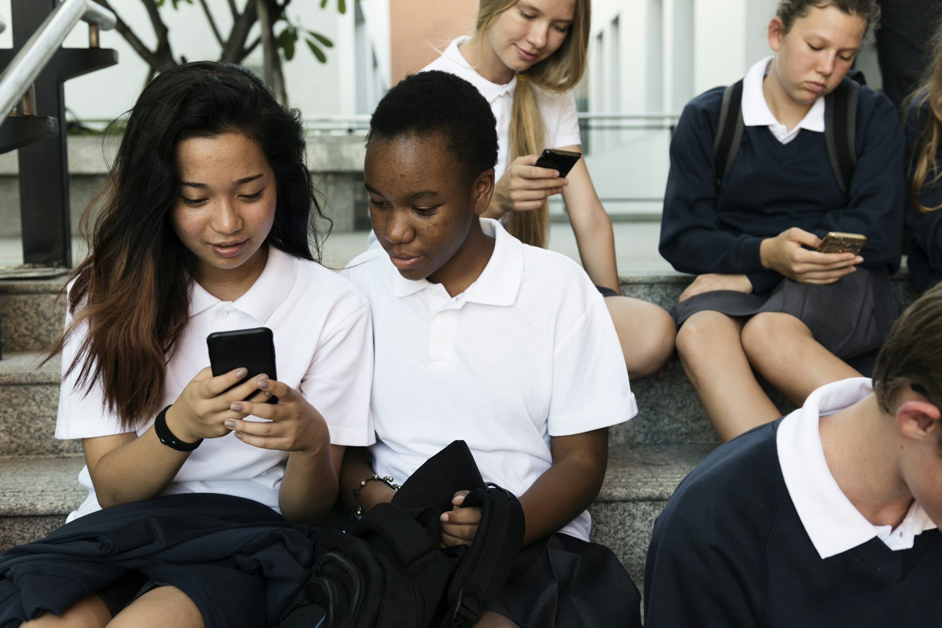 Group of children in school uniforms looking at phones