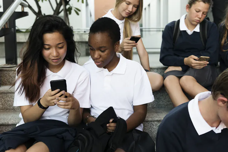 Group of children in school uniforms looking at phones