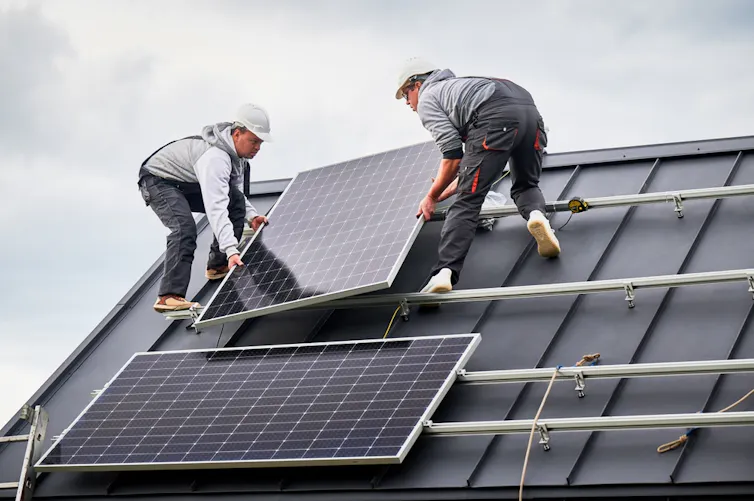 Two people installing a solar panel.