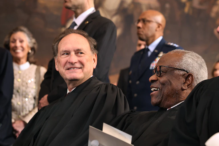 Two men in black robes laugh.