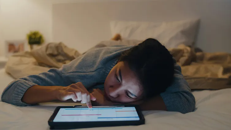 Cómo los principios de la autocompasión ayudan a combatir la soledad en la era de la inteligencia artificial 1 Una mujer en su cama hojea sola su iPad.