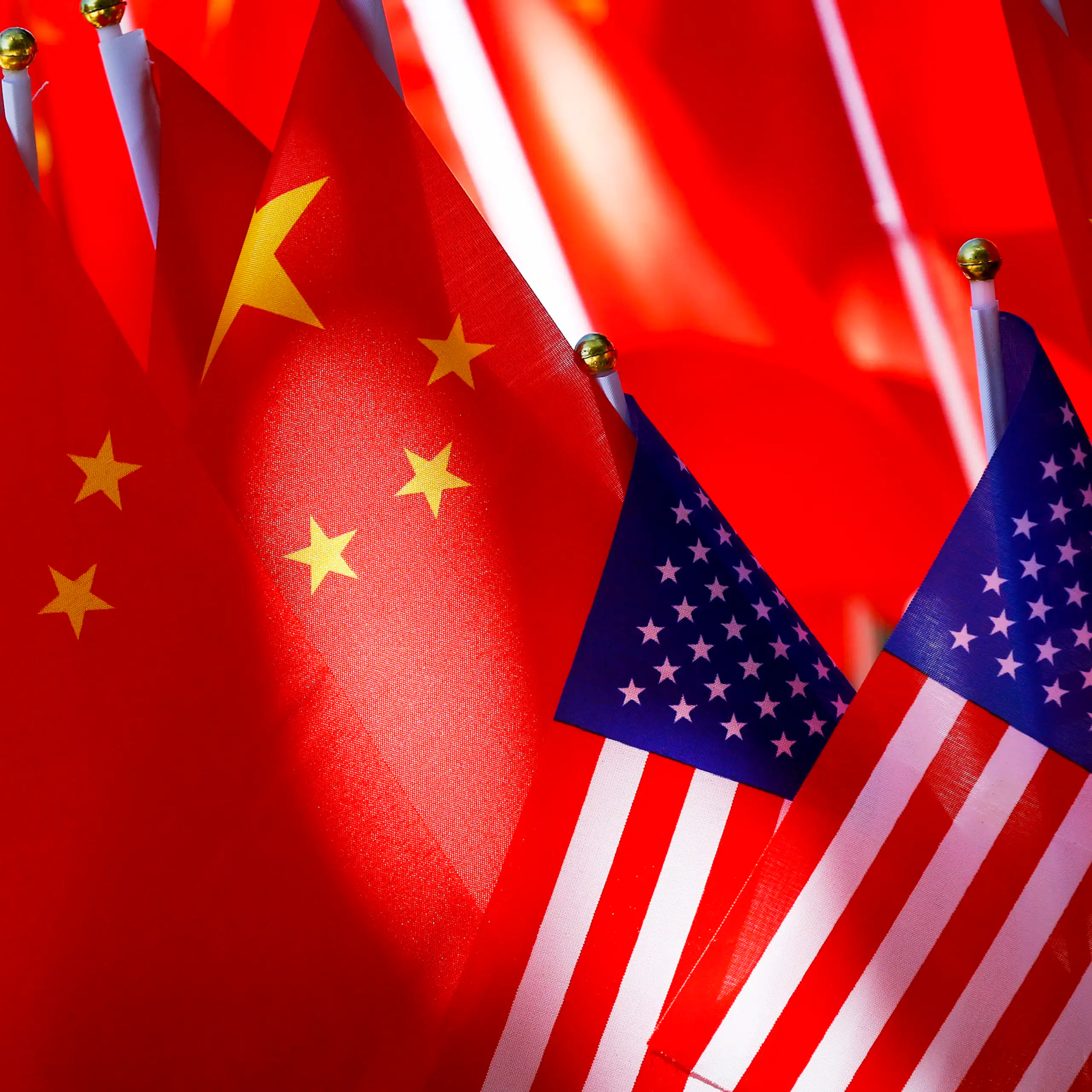 Close-up of several China flags overshadowing two US flags in the foreground