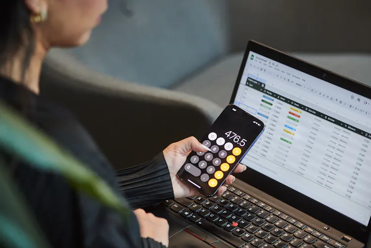 Así es como los hogares canadienses pueden apuntalar sus finanzas a prueba de recesión a medida que aumenta la incertidumbre económica 1 Una persona usa una aplicación de calculadora en su teléfono mientras trabaja en una hoja de cálculo