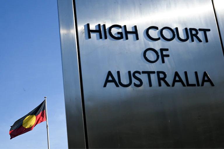 A sign saying High Court of Australia in front of an Aboriginal flag
