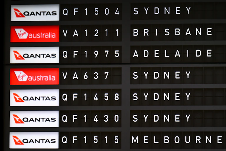 Departing flights are seen displayed on an Airport flight departure board at Canberra Airport