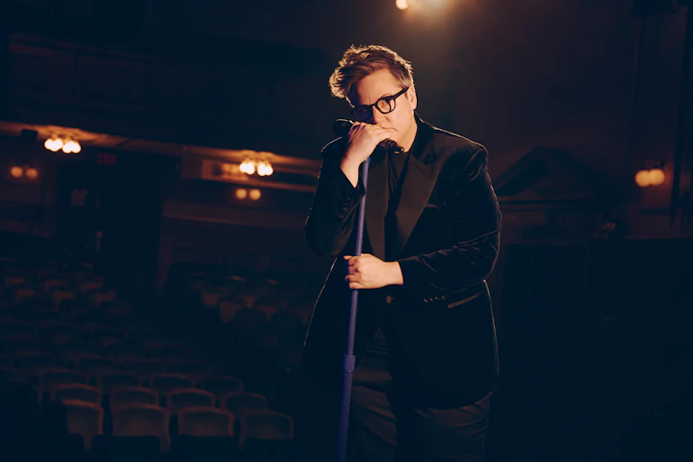 Hannah Gadsby leans on a microphone.