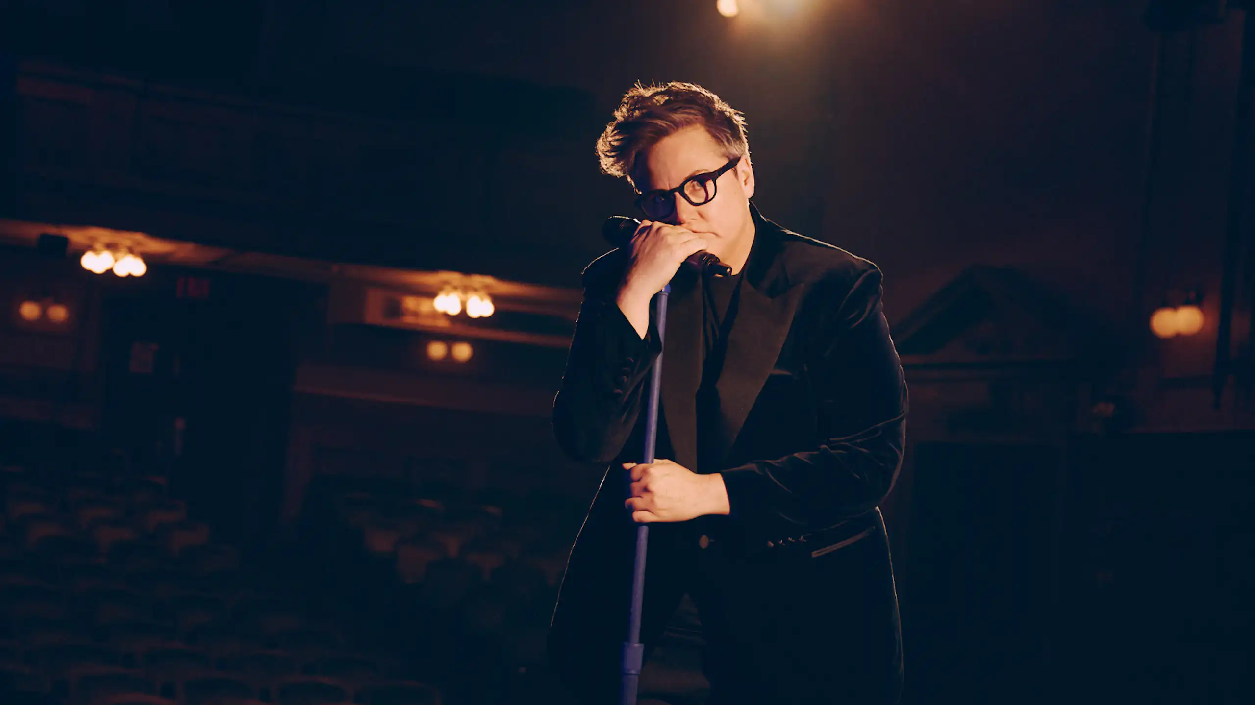 Hannah Gadsby leans on a microphone.