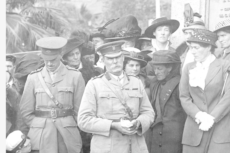 Two soilders, a child and a group of women at a memorial service during WWI.