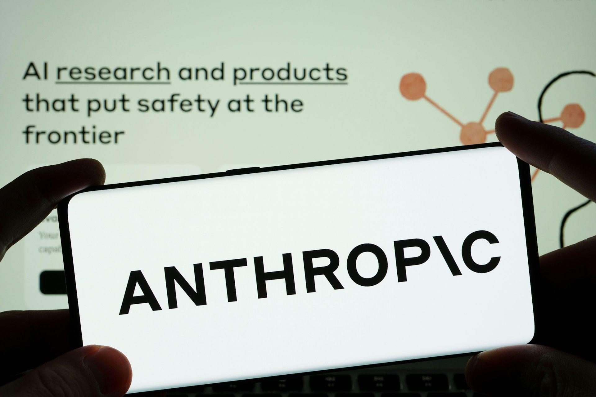 Anthropic AI research company logo on a smartphone with the company's website in the background.