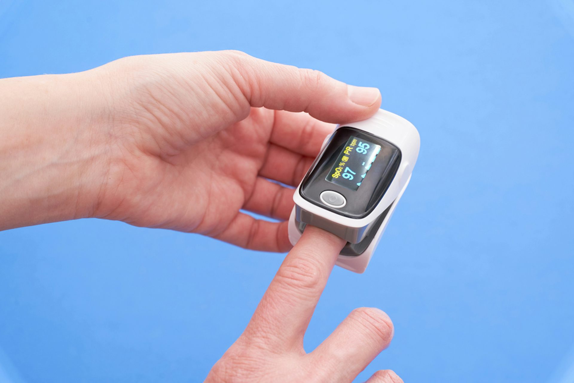 A person putting a pulse oximeter on their finger.