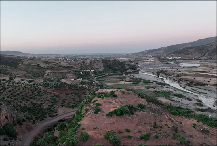 A panoramic view of a vast valley with hills in the distance and rivers running through it.