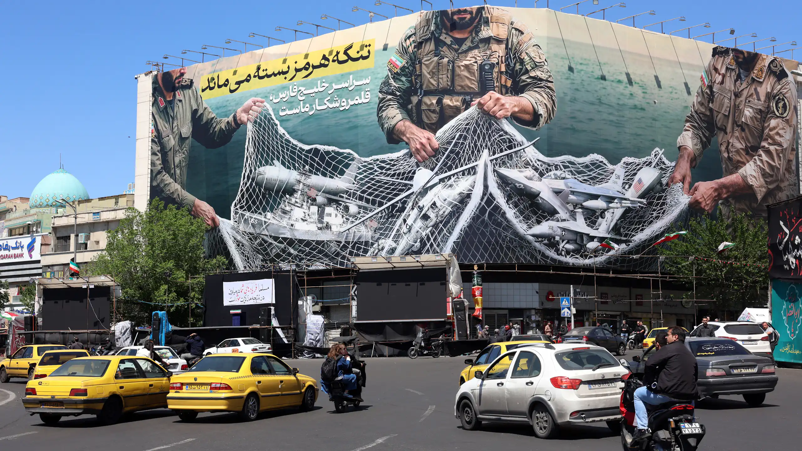 Iranians drive past a billboard carrying a sentence reading in Persian: ’The strait of Hormuz remains closed’.