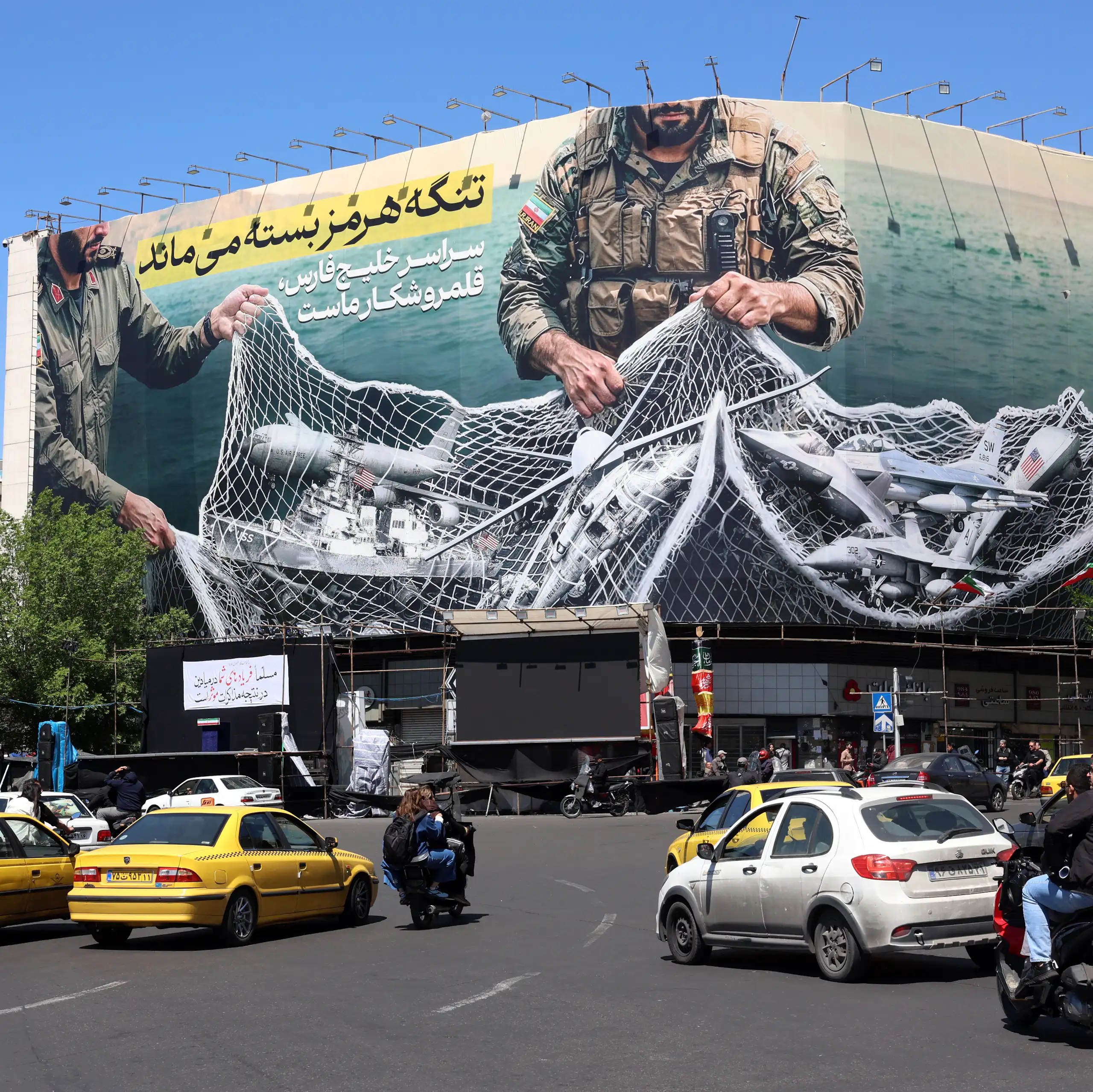 Iranians drive past a billboard carrying a sentence reading in Persian: ’The strait of Hormuz remains closed’.