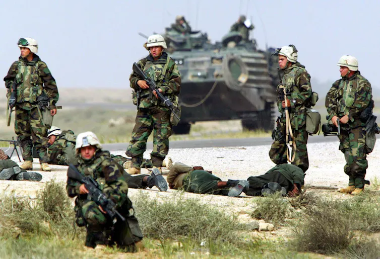 'Bombardeando nuestros pequeños corazones': cómo Trump se está aprovechando del duradero apetito de destrucción de Estados Unidos 3 Soldados fuertemente armados rodean a los hombres que yacen en el suelo. Detrás de ellos hay un tanque.