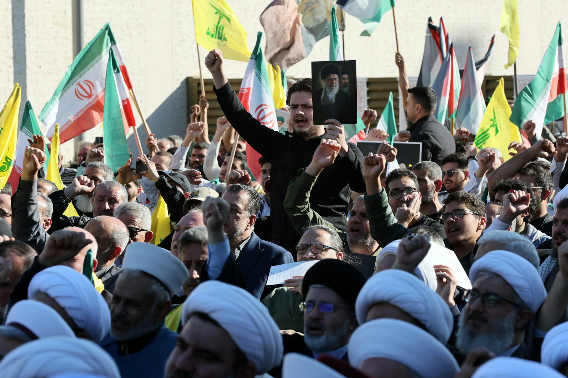 Hezbollah supporters wave Lebanese, Iranian and Hezbollah flags at a rally.