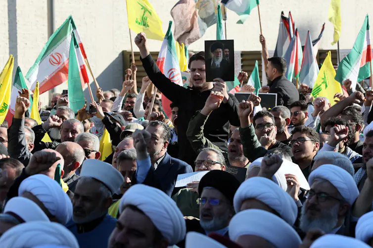 Hezbollah supporters wave Lebanese, Iranian and Hezbollah flags at a rally.
