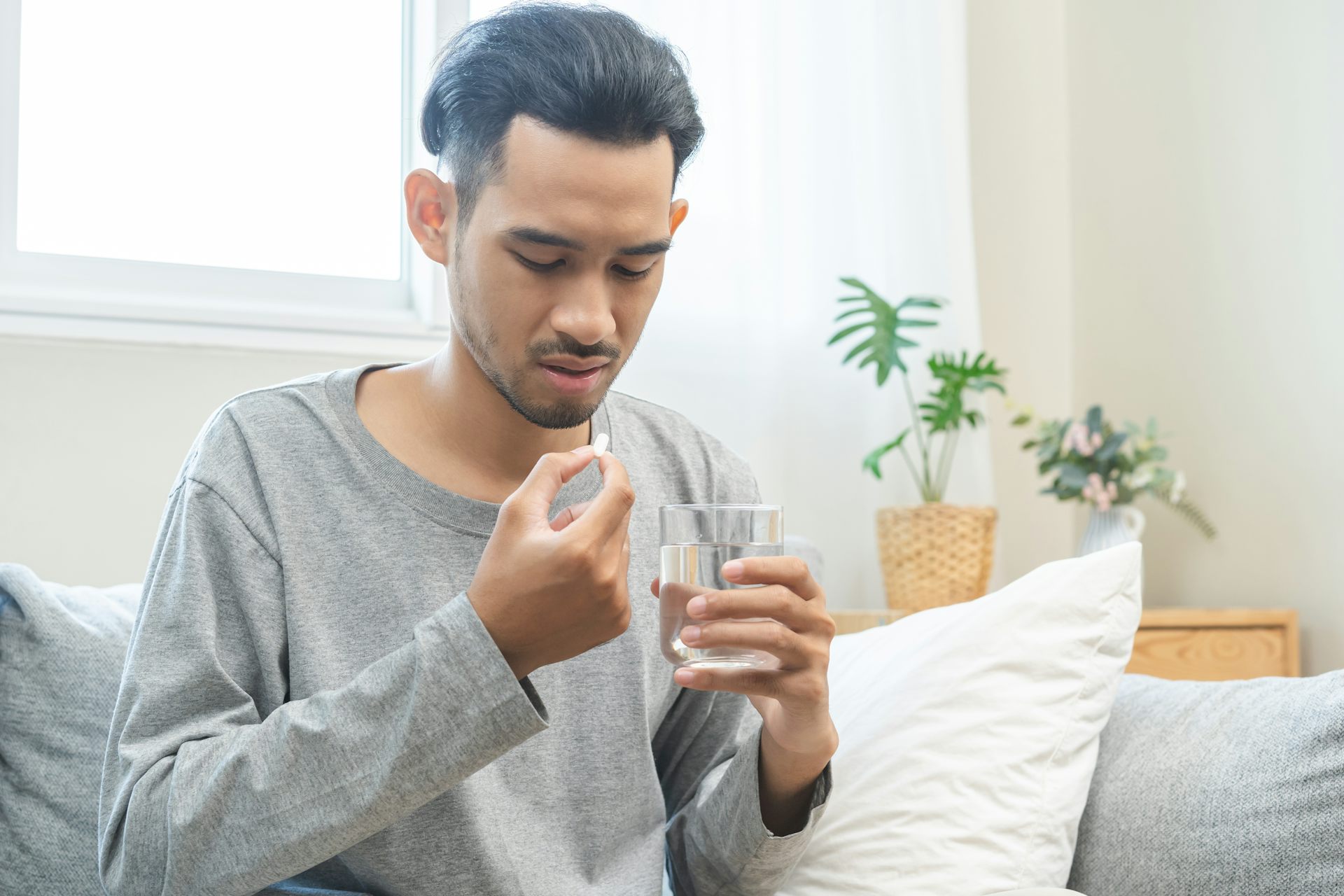 Man about to take painkiller holds glass of water
