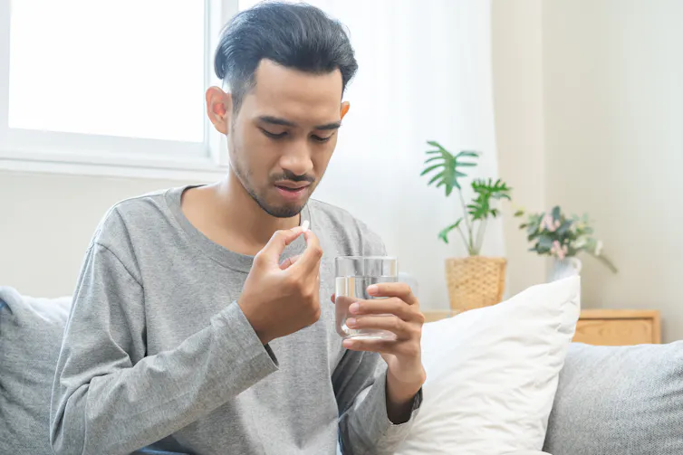 Man about to take painkiller holds glass of water