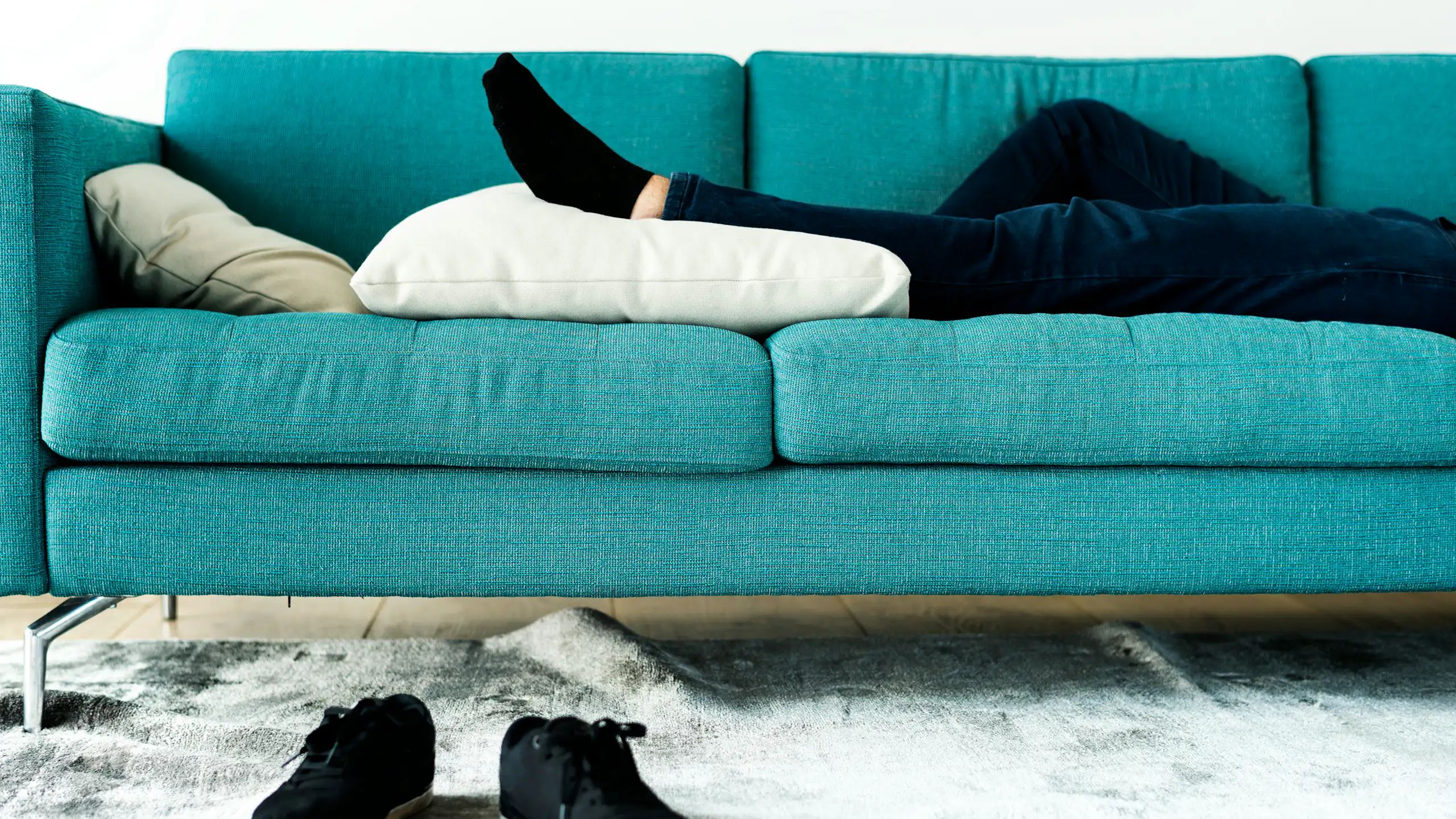 Un canapé bleu sur lequel on aperçoit les jambes et les pieds d'une personne allongée dessus