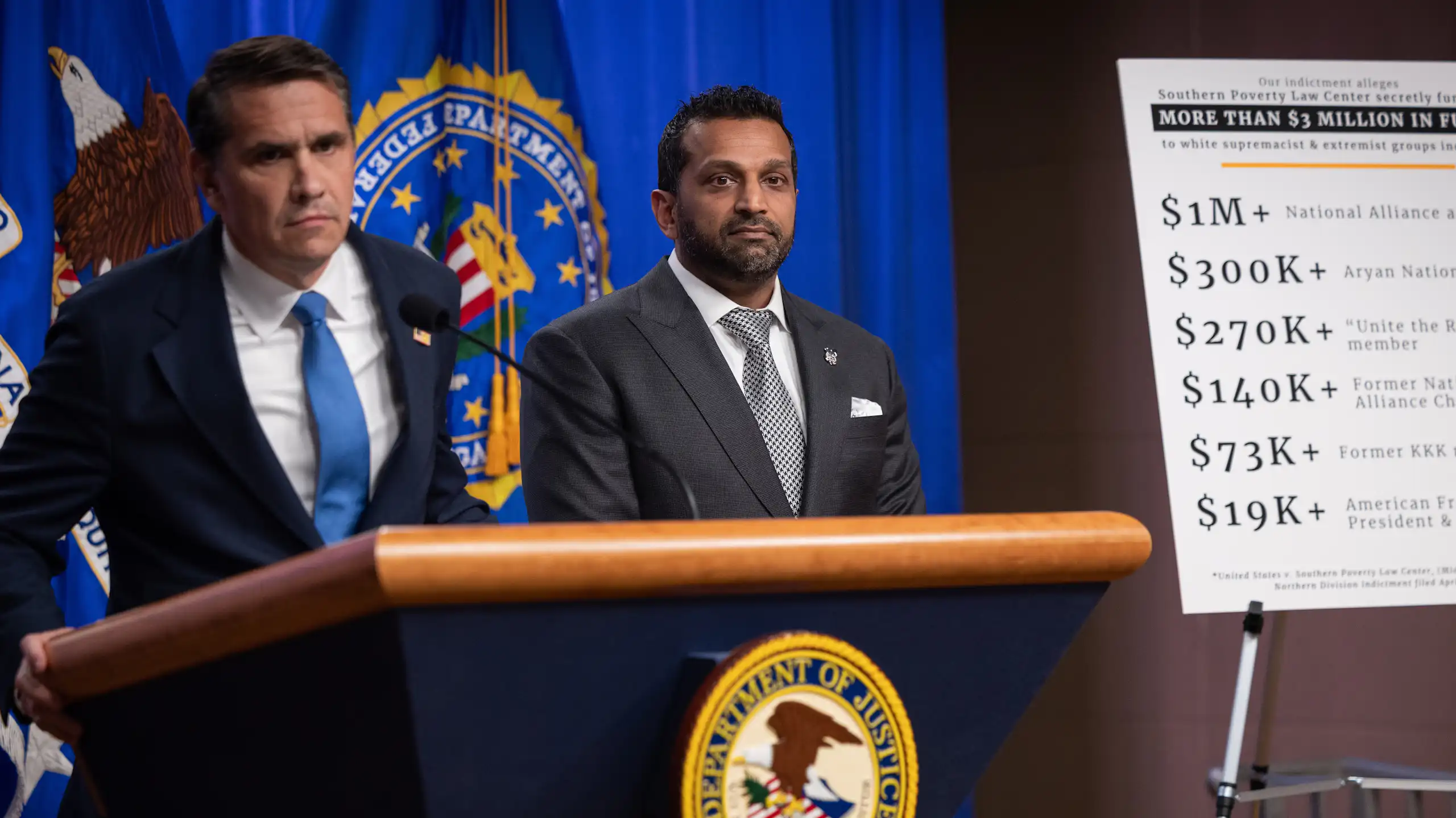Two men stand at a lectern with an official U.S. seal emblazoned upon it.