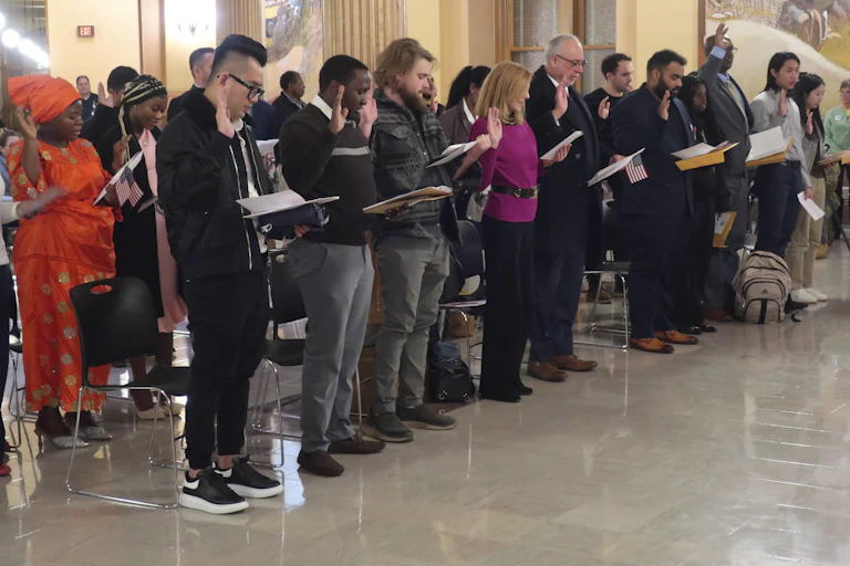 Dozens of people lift their right hands and take an oath.
