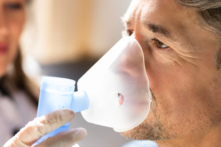 Side view of a man wearing a breath nebulizer and mask.