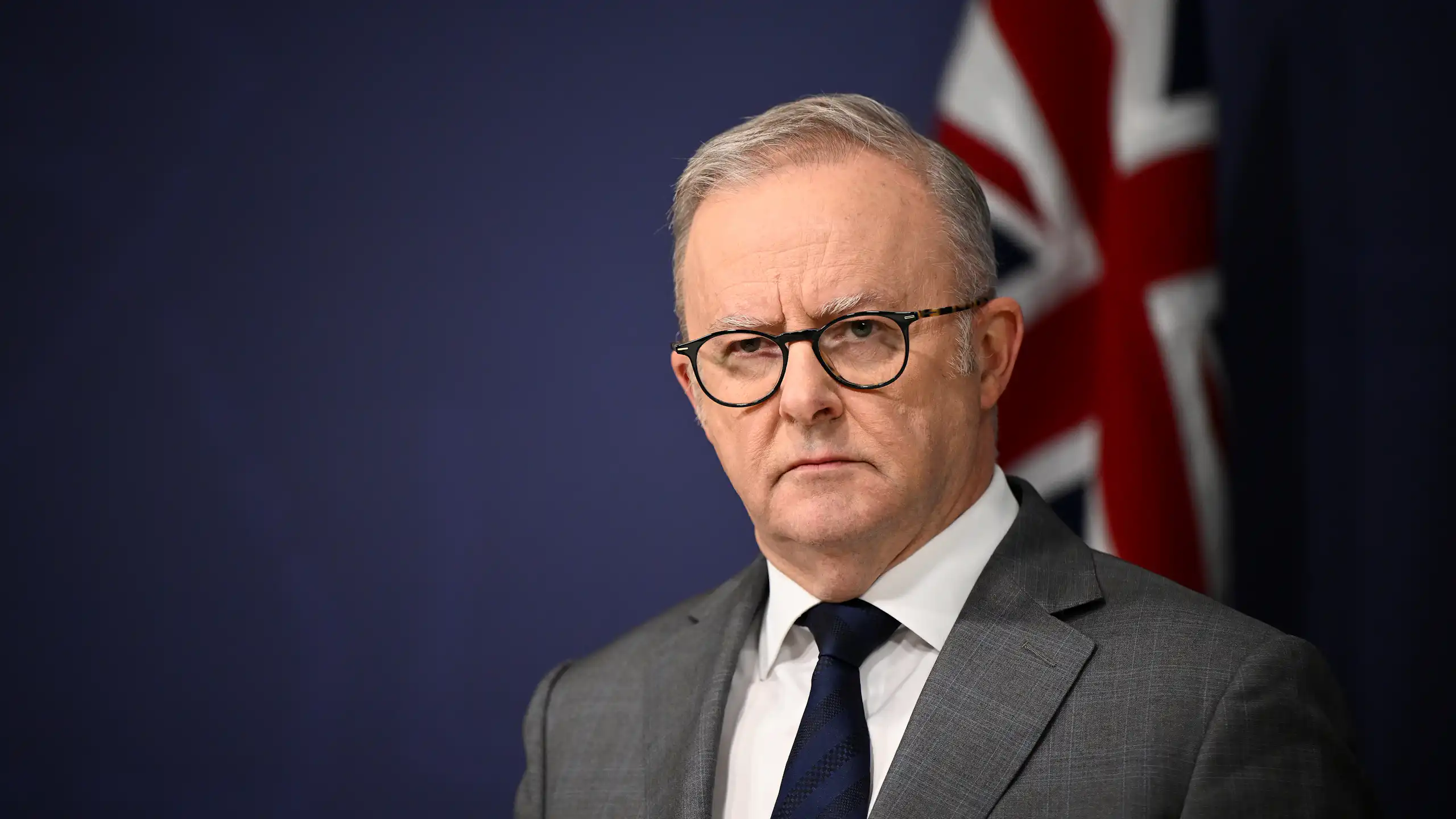 Anthony Albanese with a flag in the background