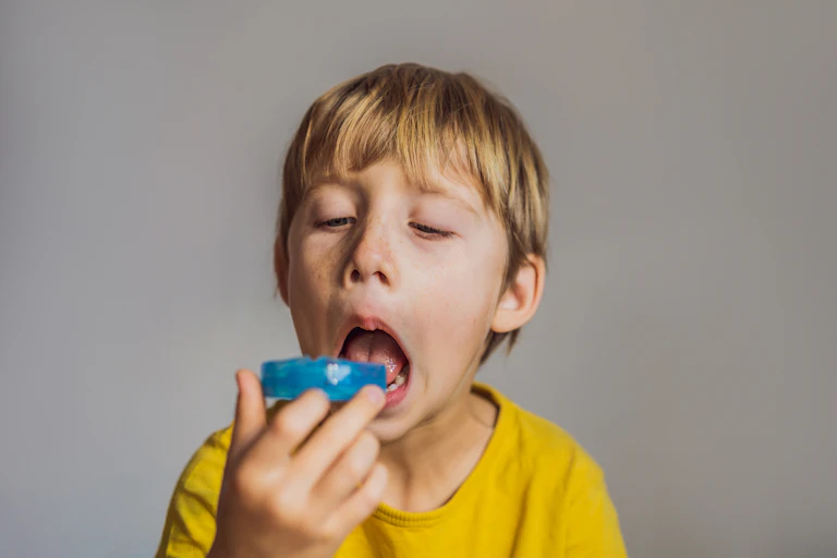 A young boy contemplates putting a mouthguard in his mouth.