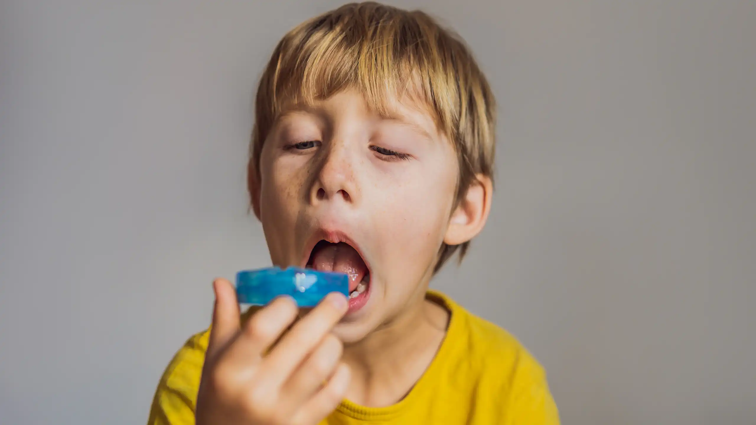 A young boy contemplates putting a mouthguard in his mouth.