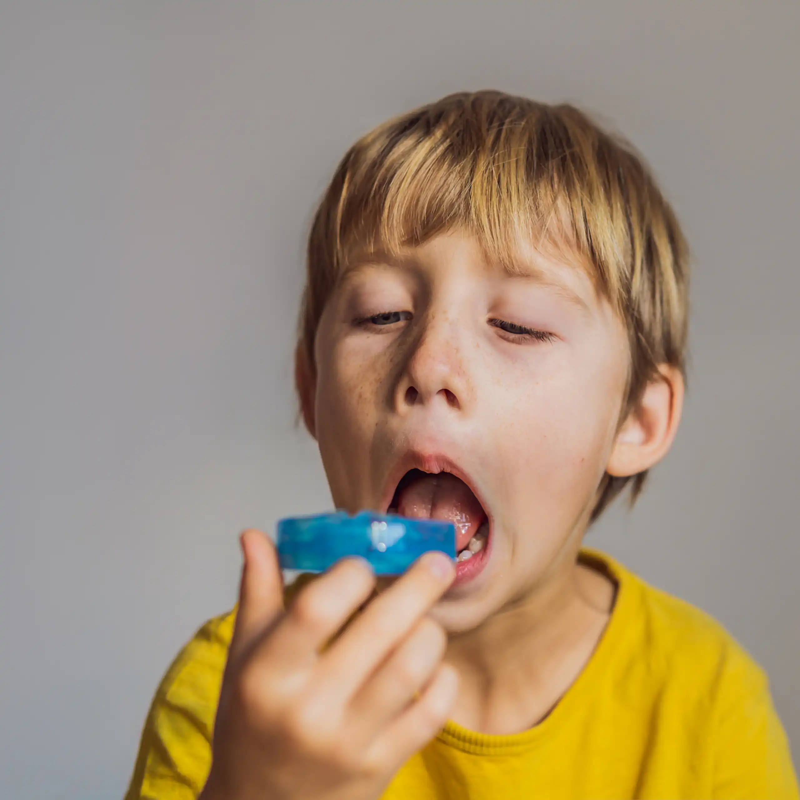 A young boy contemplates putting a mouthguard in his mouth.