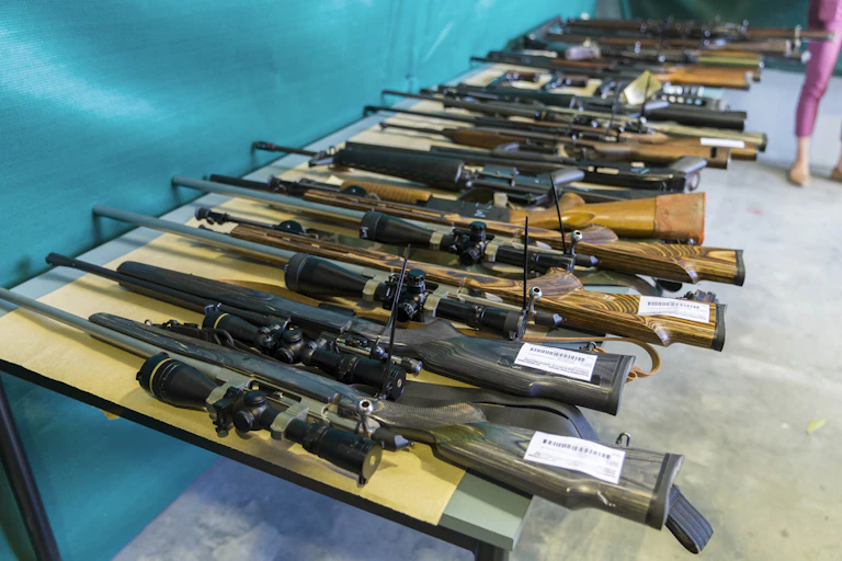 A line of large firearms lined up on a table