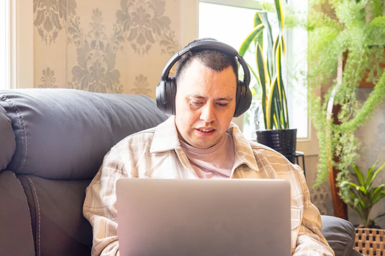 Man wearing headphones looks at laptop.