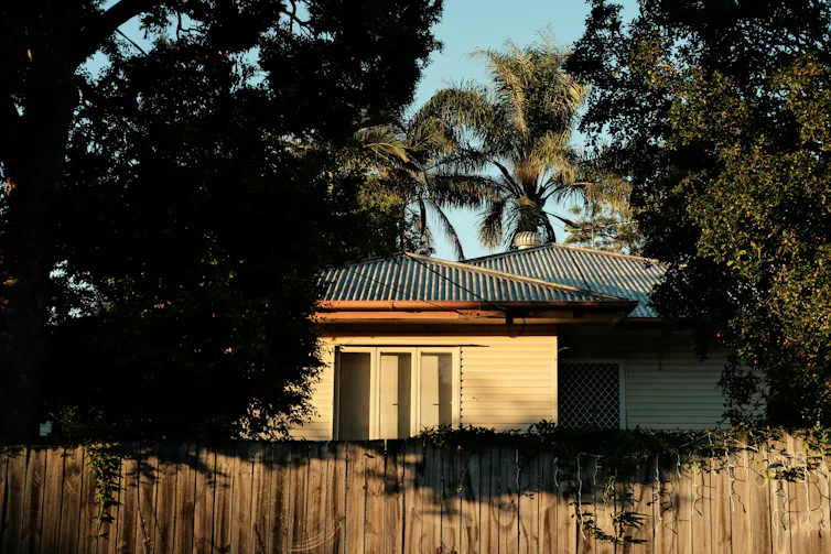 A house behind a fence surrounded by trees