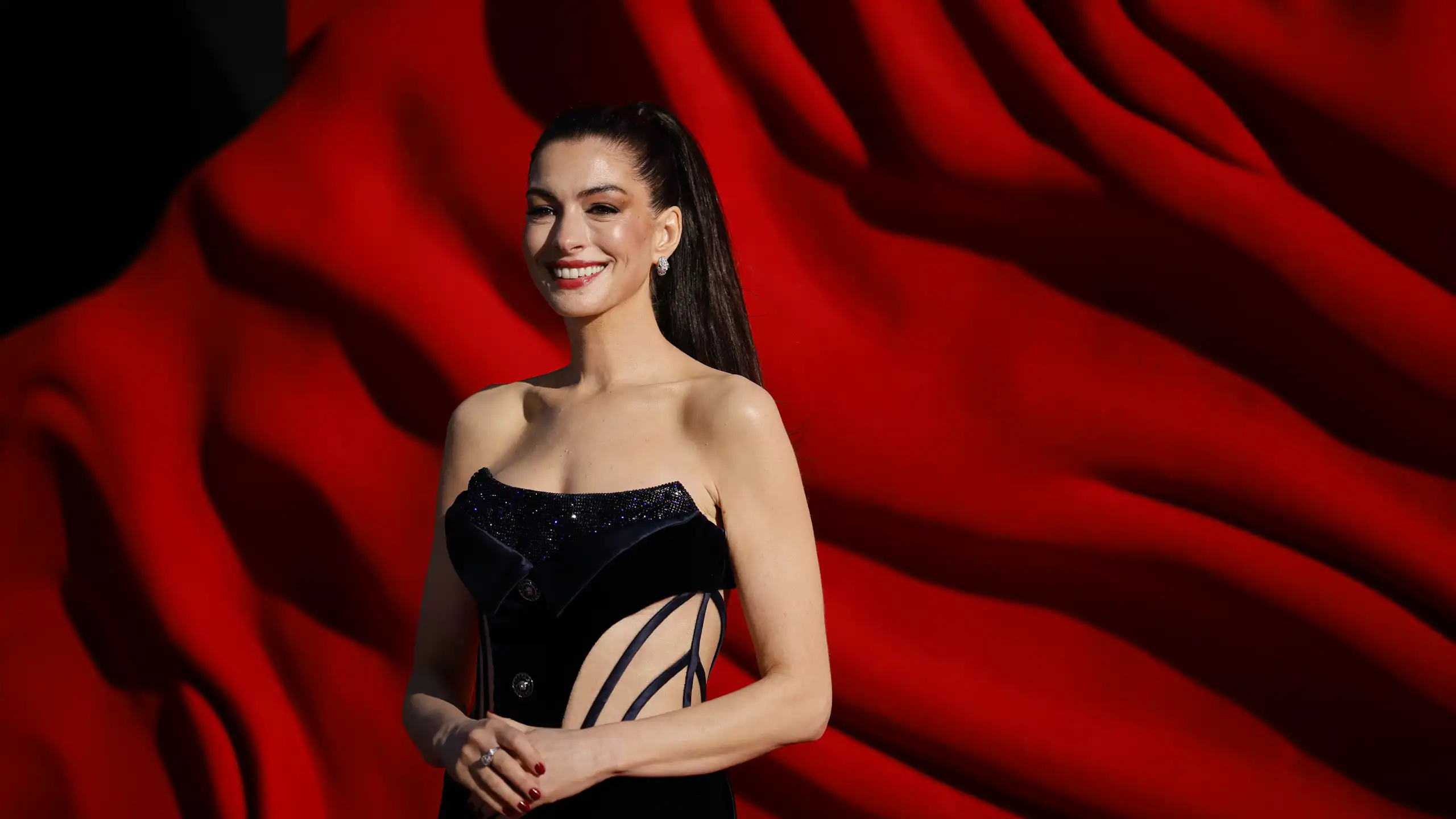 A photo of Anne Hathaway against a red background