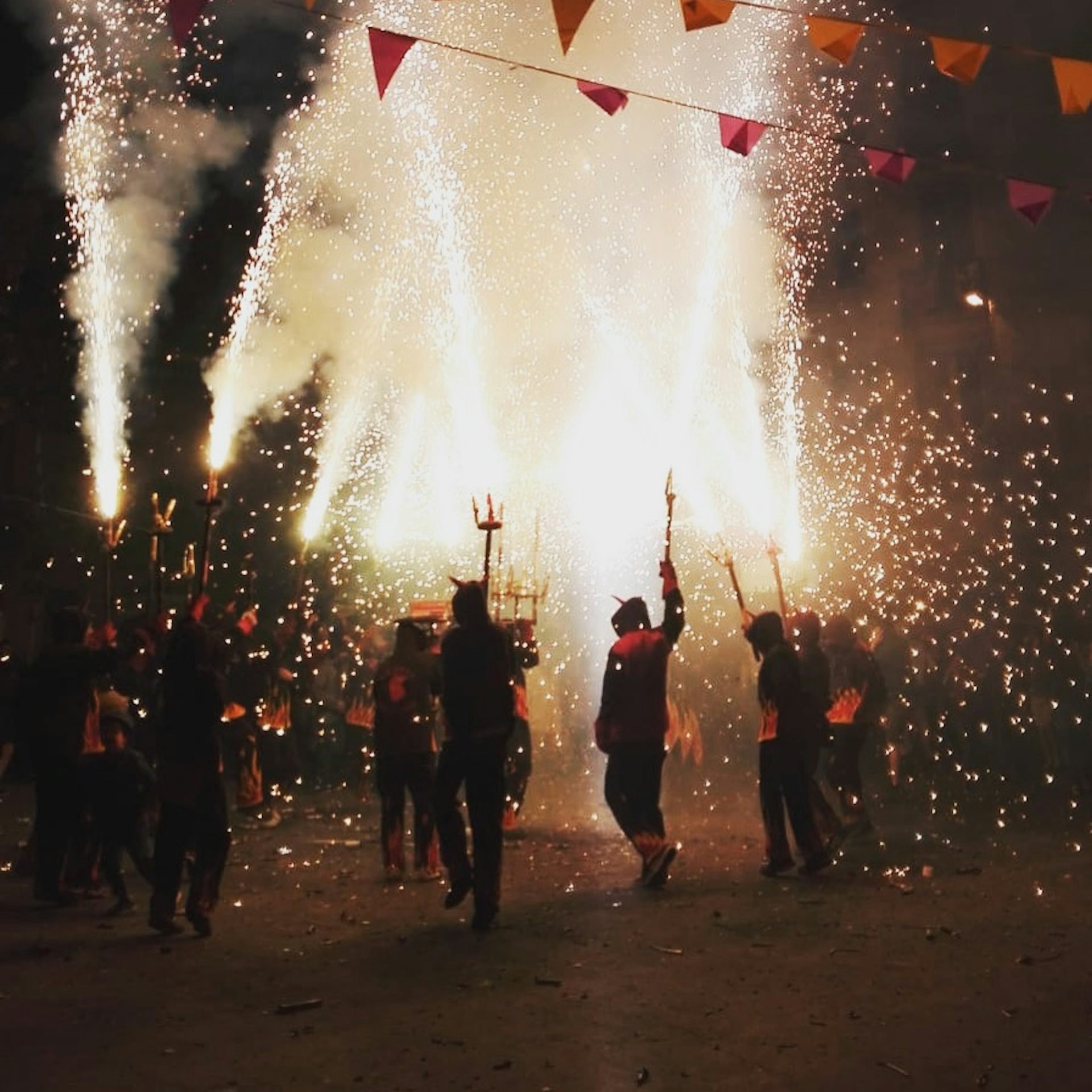 Un grupo de personas lanza fuegos artificiales por la noche.