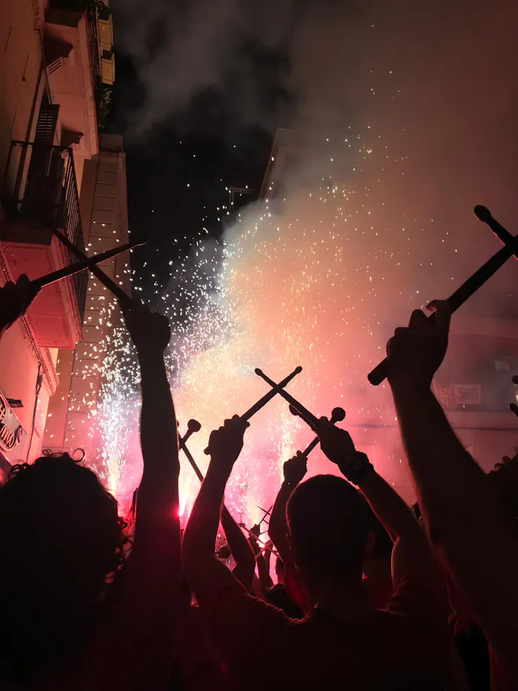 Los correfocs son la tradición más ruidosa de Barcelona, y los artistas del 'diablo de fuego' están sacrificando su oído para participar 2 Grupo de tamborileros con tambores elevados sobre sus cabezas, con fuegos artificiales de fondo.