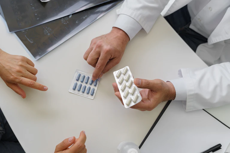 A doctor showing a patient two different blister packs of pills.