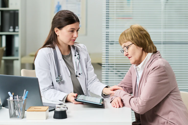 Una doctora le enseña una tableta a una paciente mayor.