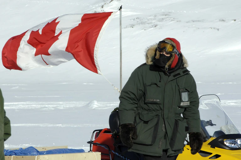 A person on a snowmobile bearing a Canadian flag.