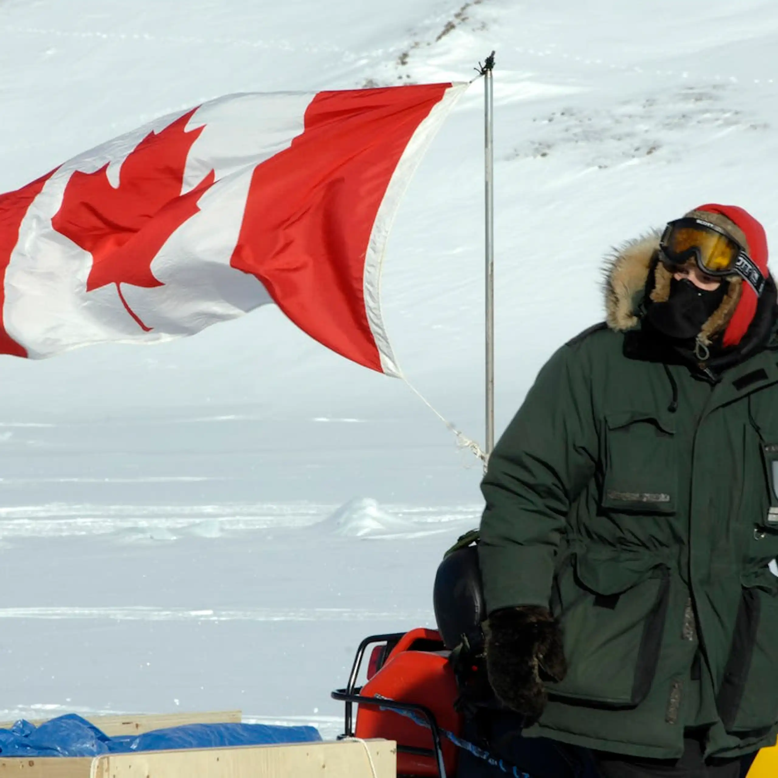 A person on a snowmobile bearing a Canadian flag.