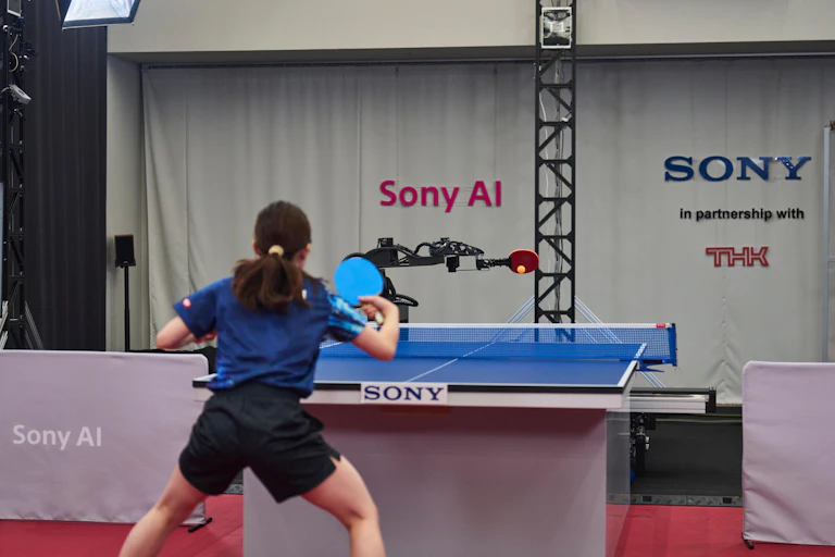 Ace fires a shot back at table tennis professional Minami Ando, during a match in April 2025.