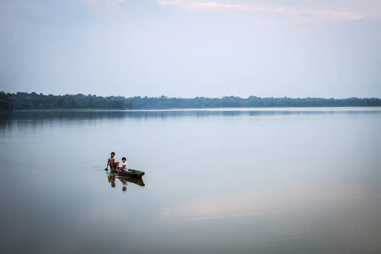 small traditional kayak on calm lake, grey sky