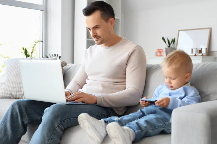 Man on laptop with young boy with mobile phone