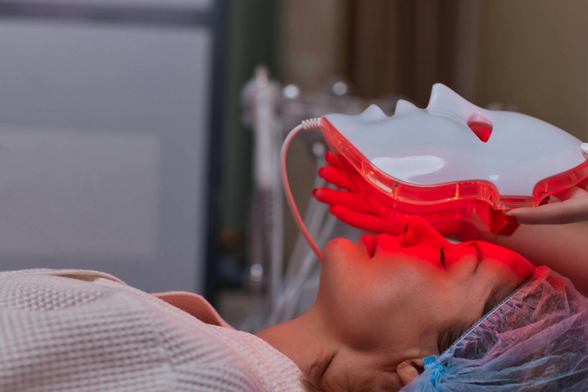 Un masque à lumière rouge est déposé sur le visage d'une femme.