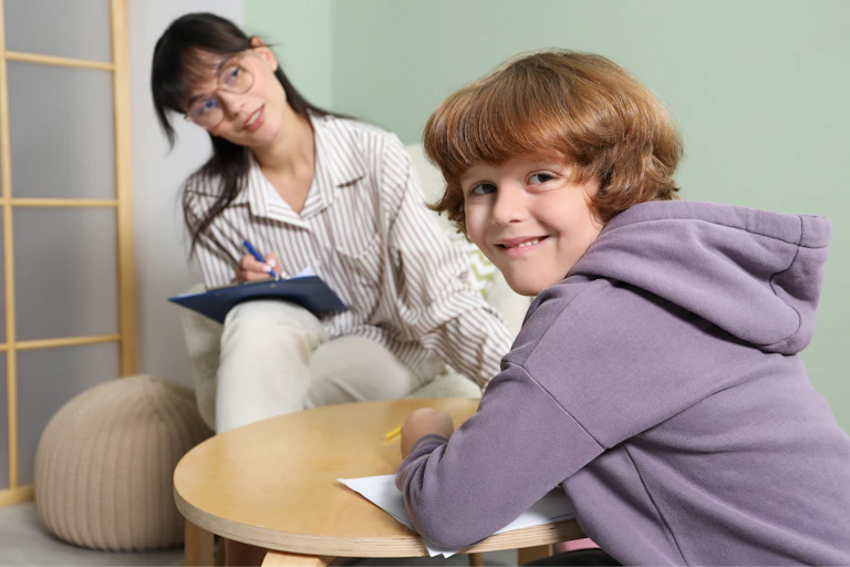 A woman with a clipboard tries to get the attention of a boy who is looking at the camera.