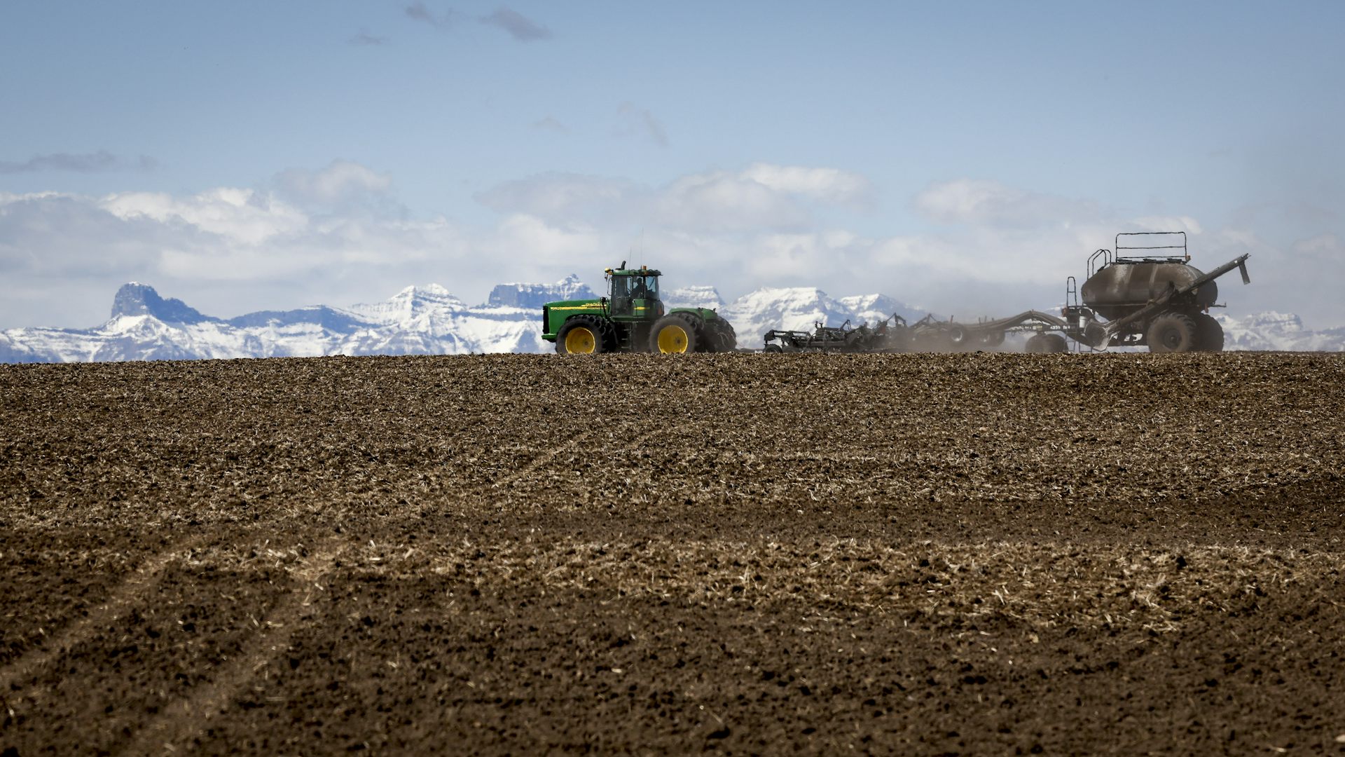 tractores en una granja marrón, montañas nevadas al fondo