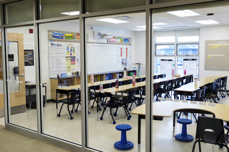 An empty classroom seen through a glass window.