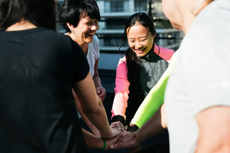 People in a circle with their hands in.