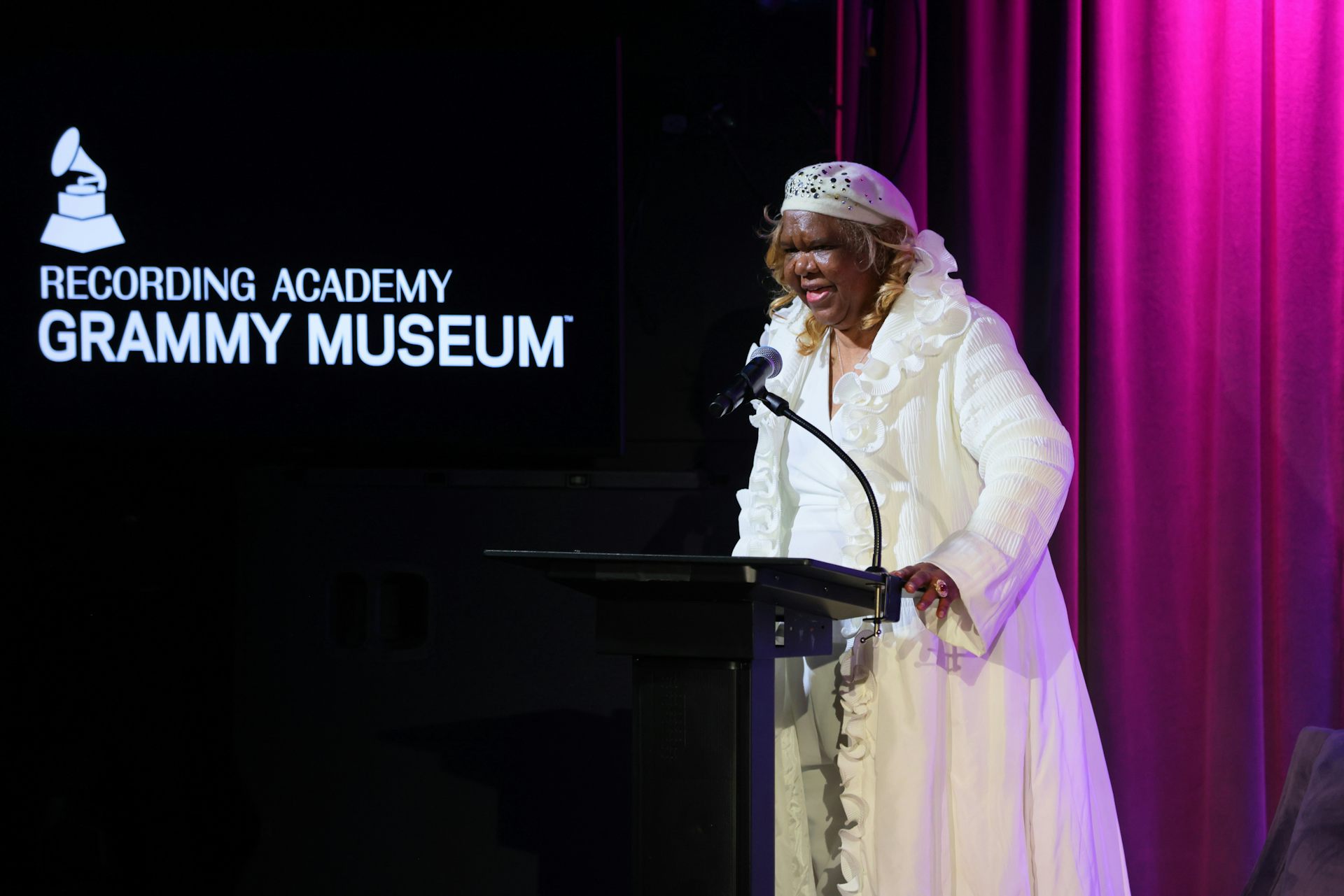 Woman stands behind a podium and speaks into a microphone.