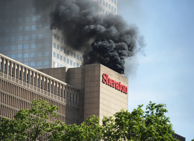Smoke billows from the top of a building labeled 'Sheraton.'